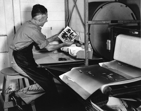 photography images of people. Description: View of Eddie Harlow examining photographic prints of 